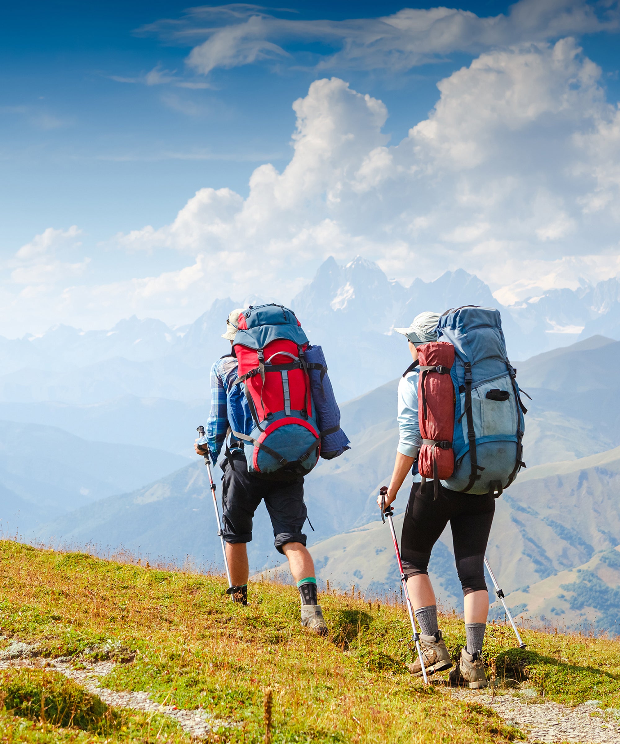 Two people hiking up a hill on a sunny day