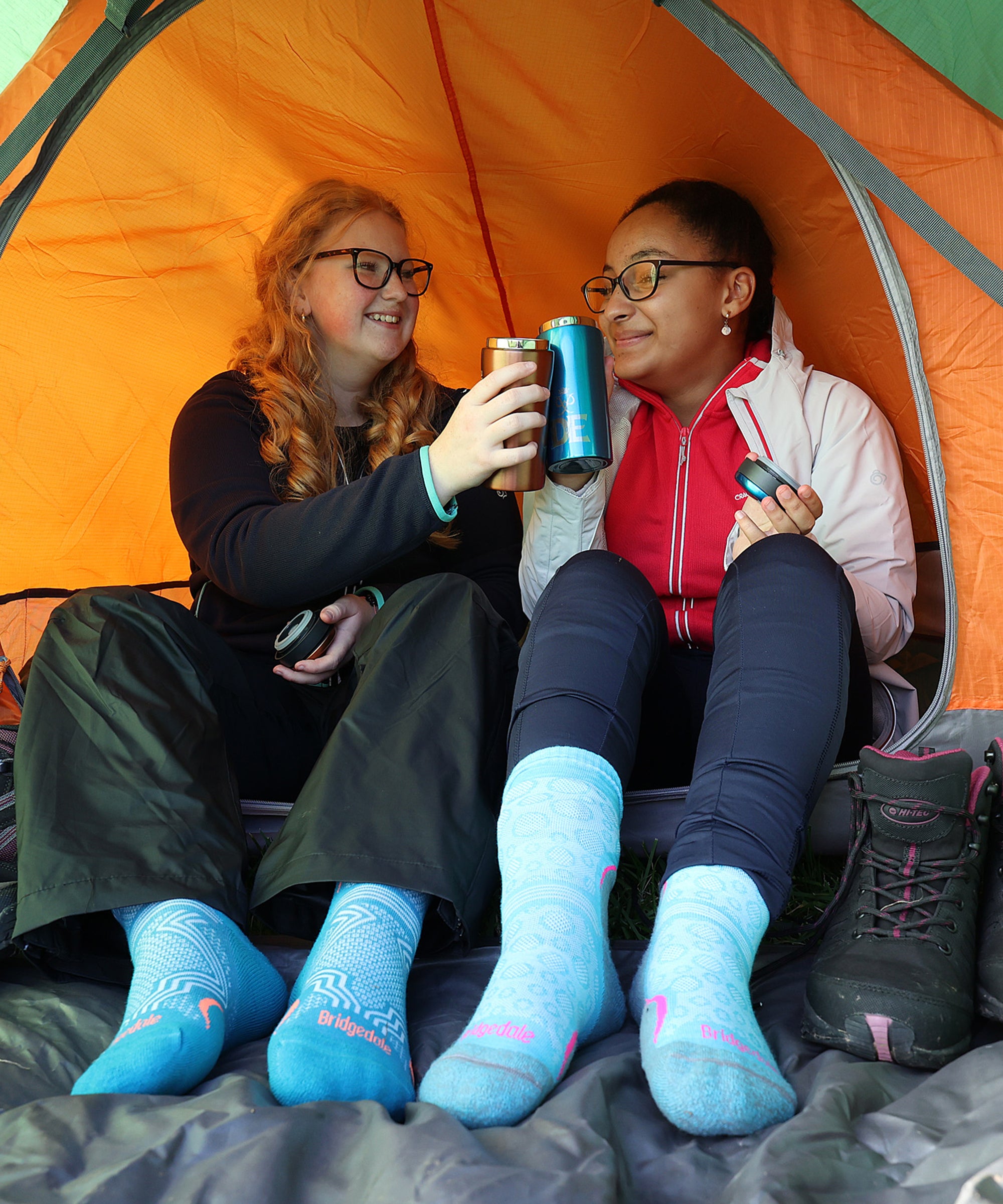 Two girls enjoying hot drinks in a tent