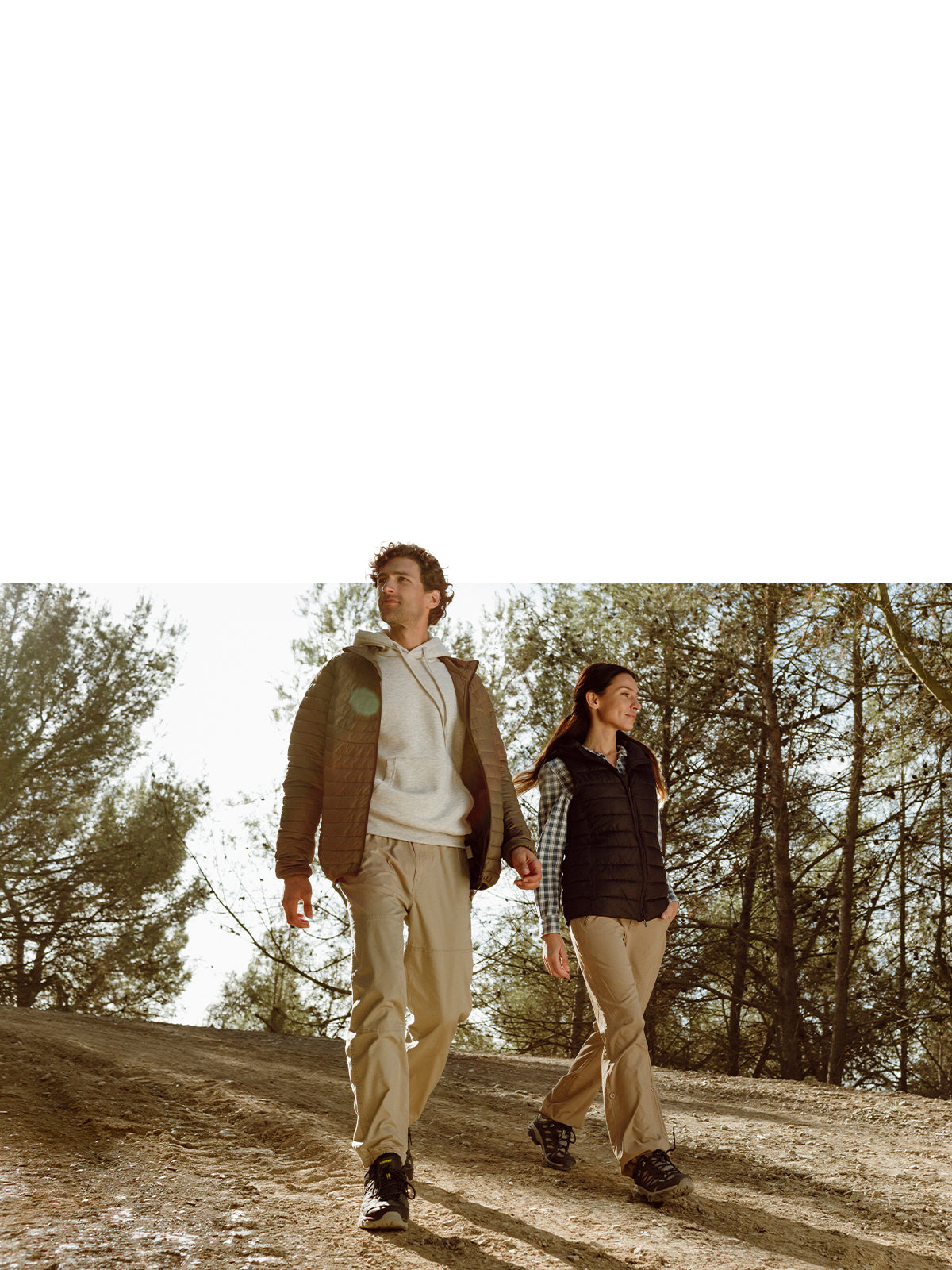 Man and woman walking through a clearing in a pine forest, wearing Hi-Tec walking boots