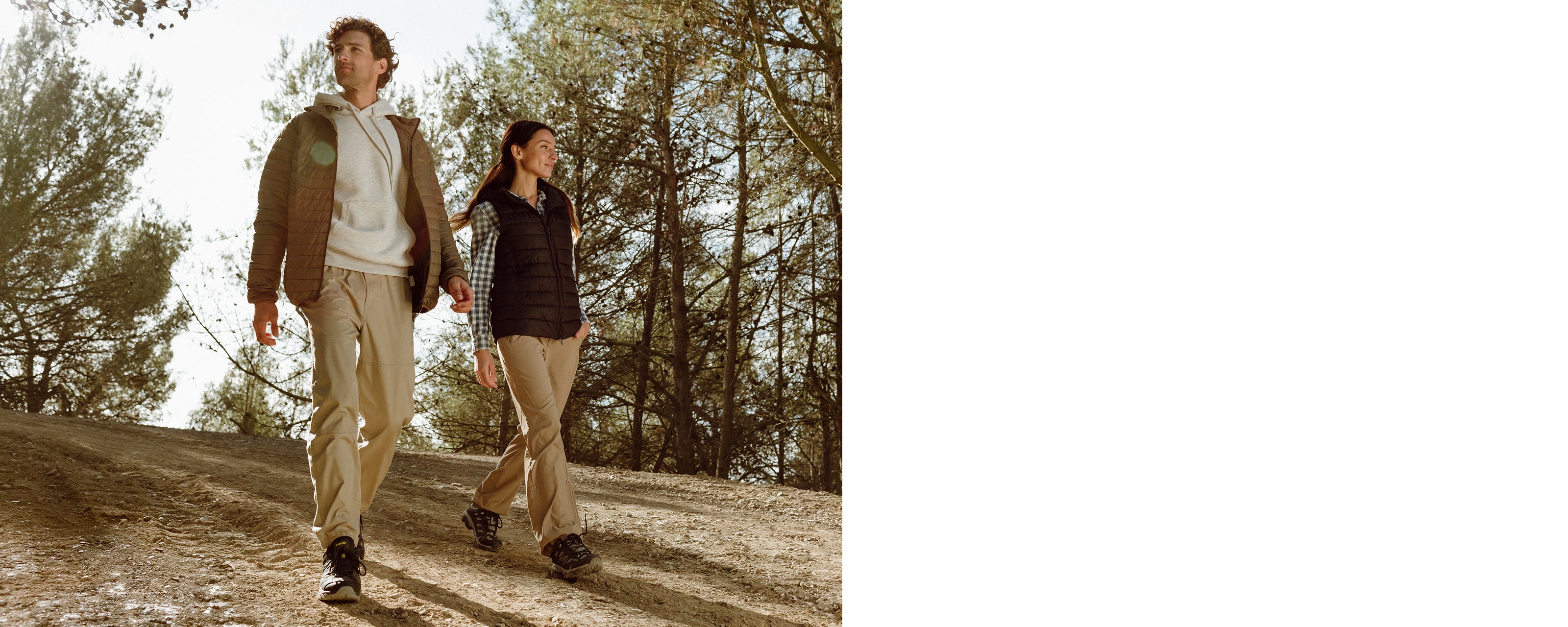Man and woman walking through a clearing in a pine forest, wearing Hi-Tec walking boots